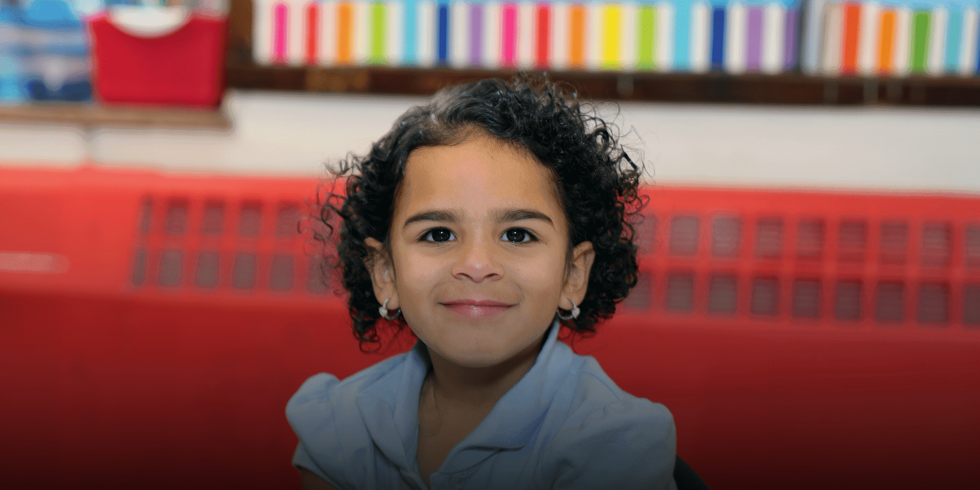 Smiling student with curly hair sitting in class.